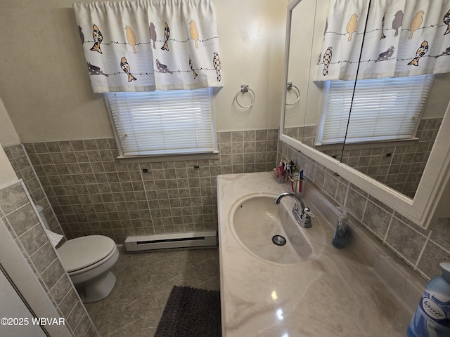 bathroom with a baseboard heating unit, tile patterned floors, toilet, and tile walls