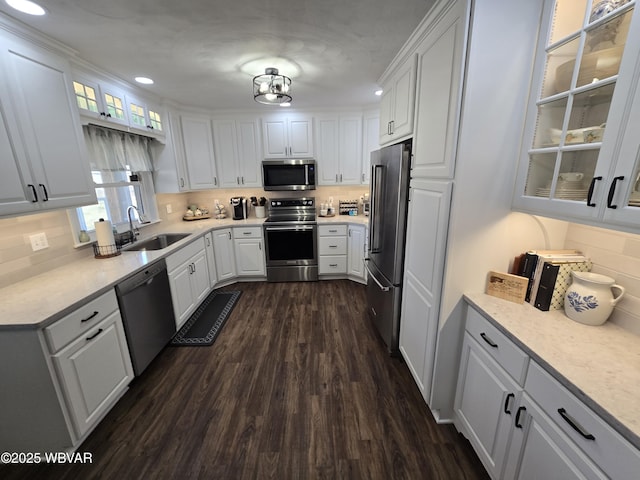 kitchen featuring backsplash, dark wood-style floors, white cabinets, stainless steel appliances, and a sink