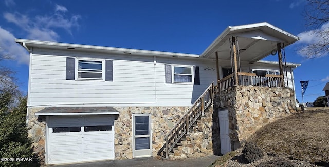 exterior space with a garage, stone siding, and stairs