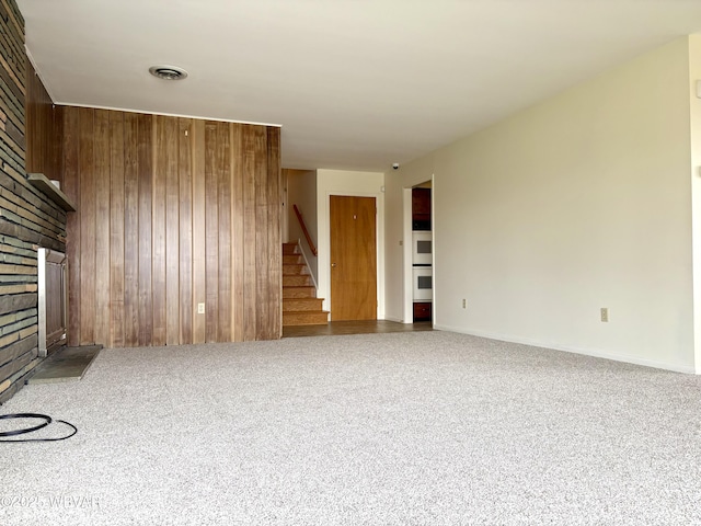 316 Winter St, Duboistown, PA 17702 - unfurnished living room with visible vents, carpet, wood walls, a large fireplace, and stairway