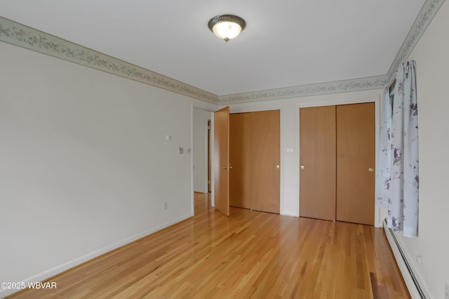 316 Winter St, Duboistown, PA 17702 - unfurnished bedroom with a baseboard radiator, two closets, baseboards, and light wood-style flooring