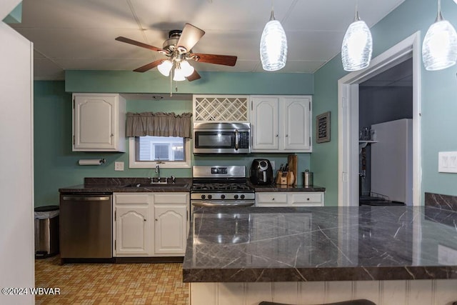 kitchen featuring ceiling fan, sink, stainless steel appliances, decorative light fixtures, and white cabinets