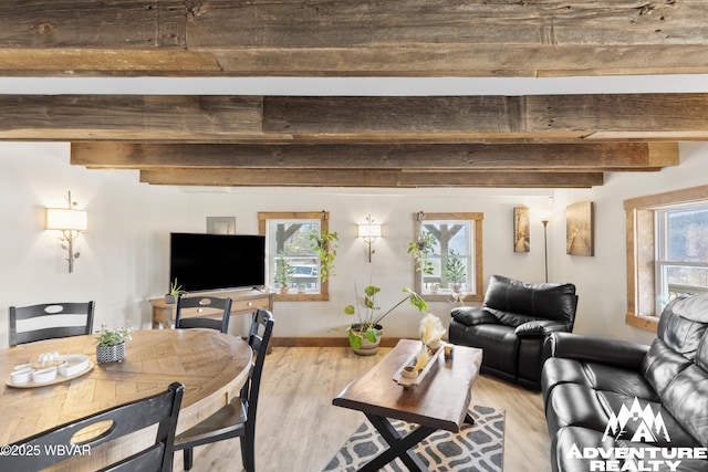 living area with a wealth of natural light, light wood-type flooring, beam ceiling, and baseboards