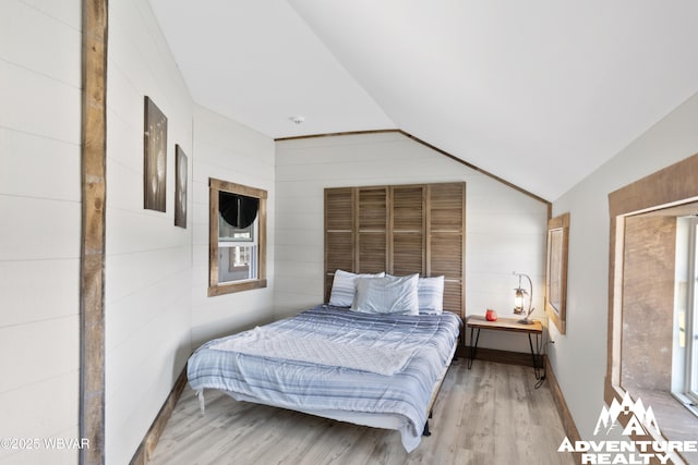 bedroom with baseboards, wood finished floors, and vaulted ceiling