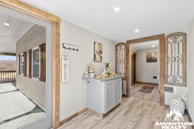 hallway featuring light wood-type flooring, baseboards, and visible vents