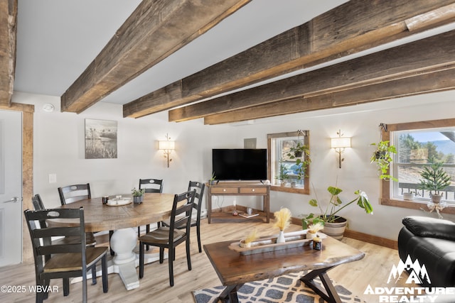 dining room featuring beamed ceiling, baseboards, and light wood finished floors