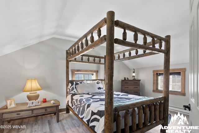 bedroom with multiple windows, lofted ceiling, and wood finished floors