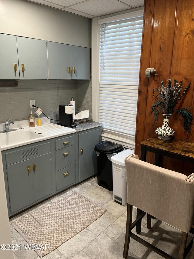 kitchen featuring a drop ceiling, decorative backsplash, sink, and light tile patterned floors