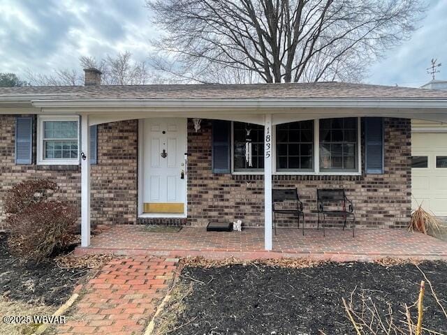 view of front of house with brick siding, a chimney, and an attached garage