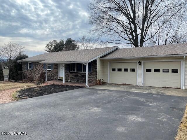 single story home featuring a garage, roof with shingles, and driveway