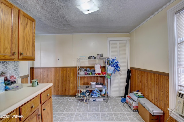 interior space featuring light tile patterned floors, a textured ceiling, wooden walls, and crown molding