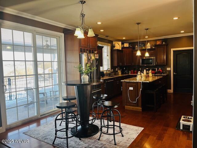 kitchen featuring stainless steel appliances, a kitchen island, a healthy amount of sunlight, and pendant lighting