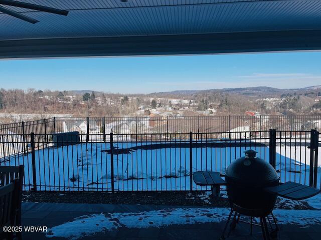 snow covered pool featuring a mountain view and a patio area