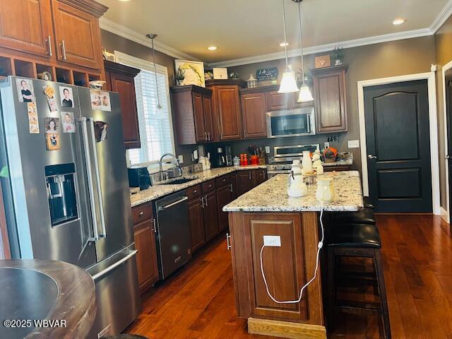 kitchen featuring pendant lighting, appliances with stainless steel finishes, sink, and a kitchen island