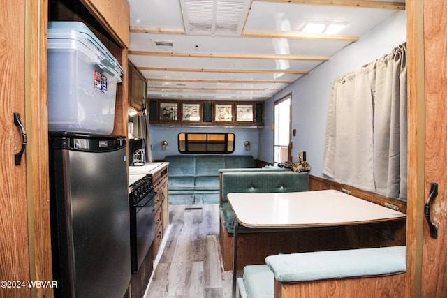 kitchen featuring stainless steel refrigerator, black range oven, and light hardwood / wood-style floors