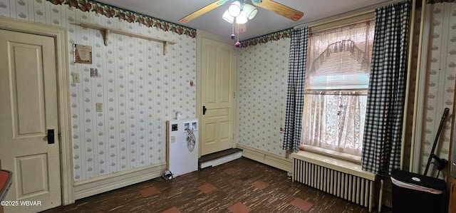 unfurnished room with ceiling fan, wallpapered walls, and dark floors
