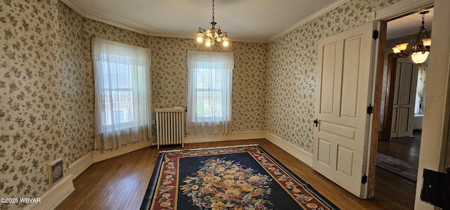unfurnished dining area with crown molding, a notable chandelier, wood finished floors, and radiator heating unit