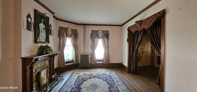unfurnished room featuring radiator heating unit, baseboards, wood finished floors, and crown molding
