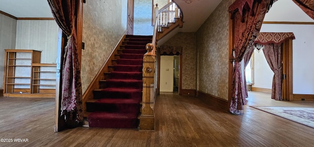 stairs featuring wood finished floors, crown molding, and baseboards