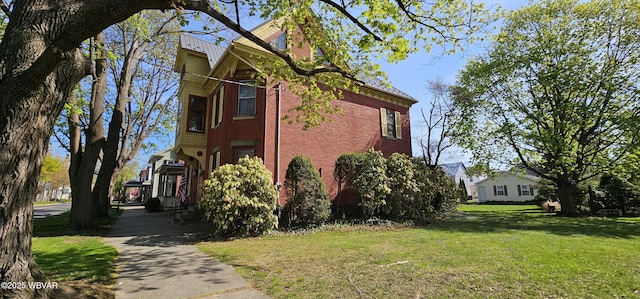 view of home's exterior with brick siding and a yard