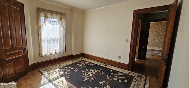 spare room with baseboards, ornamental molding, and wood finished floors