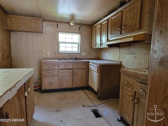 kitchen featuring white dishwasher, tile countertops, brown cabinetry, and a sink