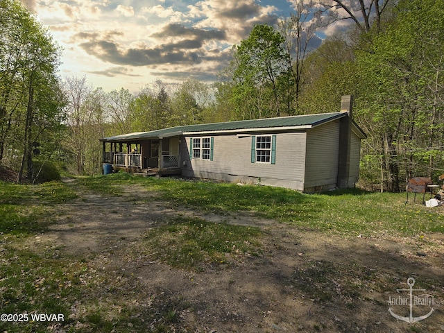 manufactured / mobile home featuring a porch, crawl space, a chimney, and metal roof