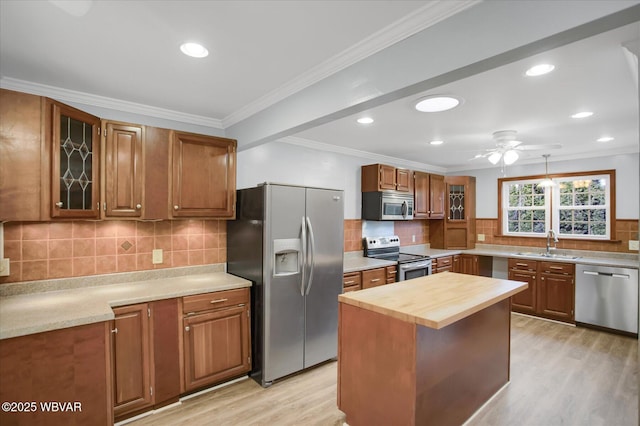 kitchen with a kitchen island, sink, wooden counters, stainless steel appliances, and crown molding