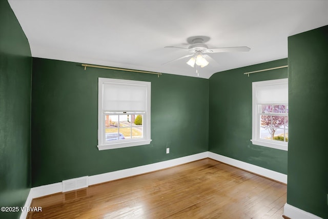 empty room with ceiling fan, wood-type flooring, and a healthy amount of sunlight