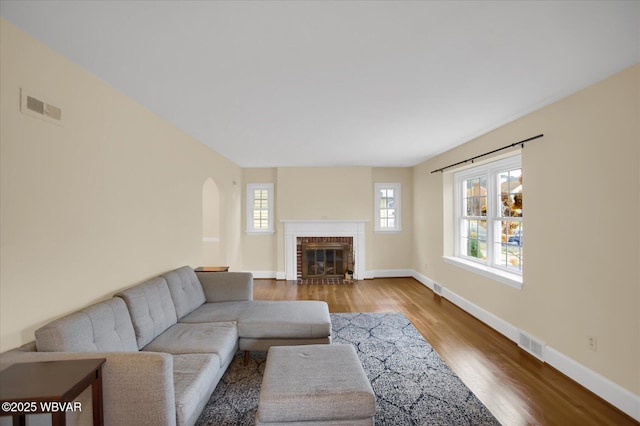 living room with wood-type flooring and a brick fireplace