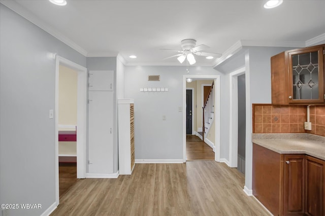 interior space featuring tasteful backsplash, ornamental molding, ceiling fan, and light hardwood / wood-style flooring