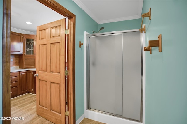 bathroom featuring ornamental molding, an enclosed shower, and wood-type flooring