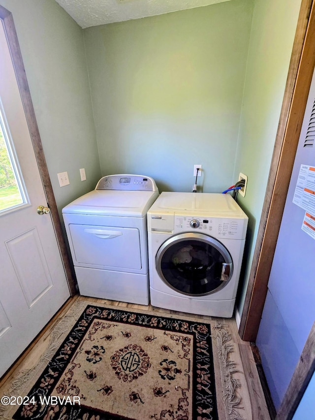 laundry room with washer and clothes dryer, light hardwood / wood-style floors, and a textured ceiling