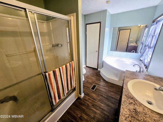 full bathroom featuring vanity, toilet, wood-type flooring, and shower with separate bathtub