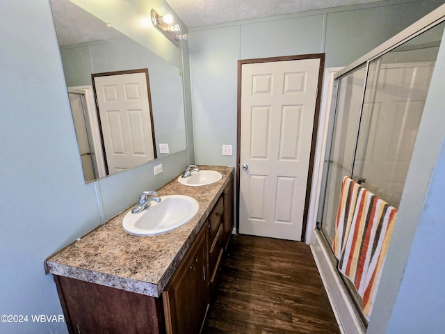 bathroom with vanity, a textured ceiling, hardwood / wood-style flooring, and a shower with door