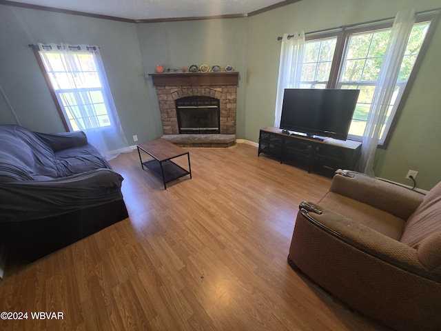 living room featuring hardwood / wood-style flooring, a fireplace, a healthy amount of sunlight, and crown molding