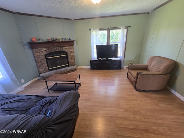 living room with a stone fireplace, wood-type flooring, a textured ceiling, and ornamental molding