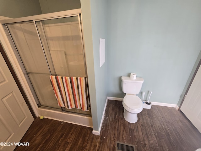 bathroom with wood-type flooring, a shower with shower door, and toilet