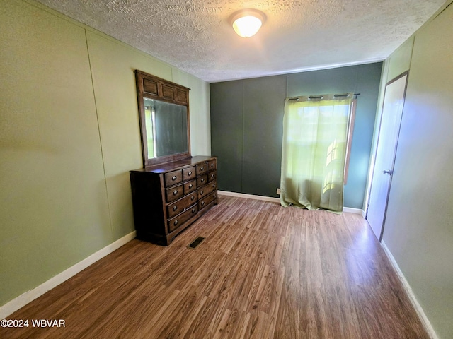 bedroom featuring hardwood / wood-style floors, a textured ceiling, and multiple windows