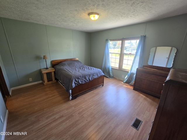 bedroom featuring hardwood / wood-style floors and a textured ceiling