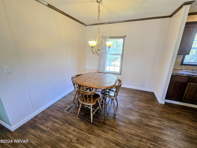 dining space featuring sink, an inviting chandelier, dark wood-type flooring, and crown molding