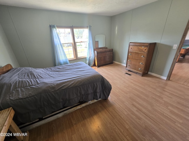 bedroom featuring a textured ceiling and light hardwood / wood-style flooring