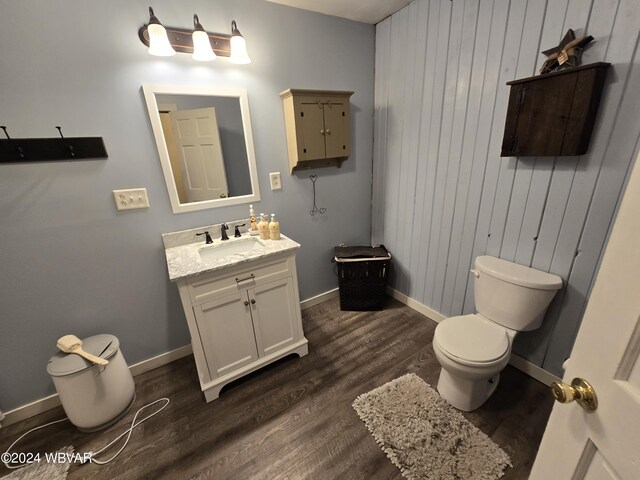 bathroom featuring hardwood / wood-style floors, vanity, toilet, and wood walls