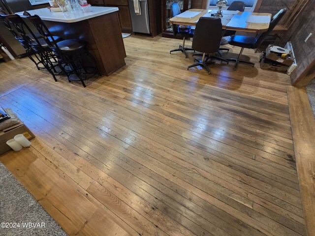 dining space featuring wooden walls, light hardwood / wood-style flooring, and indoor bar