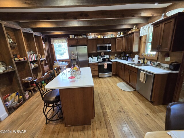 kitchen with appliances with stainless steel finishes, sink, light hardwood / wood-style floors, a kitchen island, and a breakfast bar area