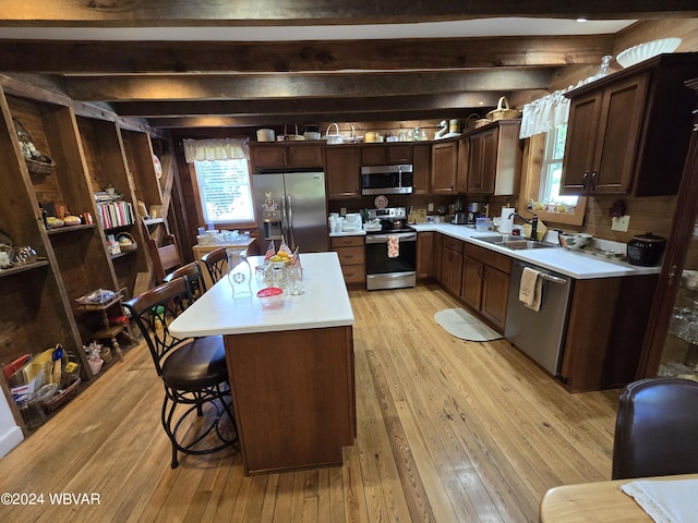 kitchen featuring sink, stainless steel appliances, light hardwood / wood-style flooring, a kitchen bar, and a kitchen island