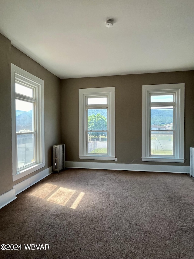 carpeted spare room featuring radiator, radiator heating unit, and baseboards