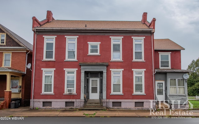 view of front facade featuring entry steps, brick siding, and a chimney