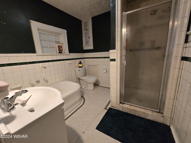 bathroom with tile patterned flooring, toilet, tile walls, and an enclosed shower