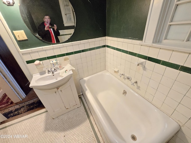 bathroom featuring a tub, tile patterned flooring, vanity, and tile walls